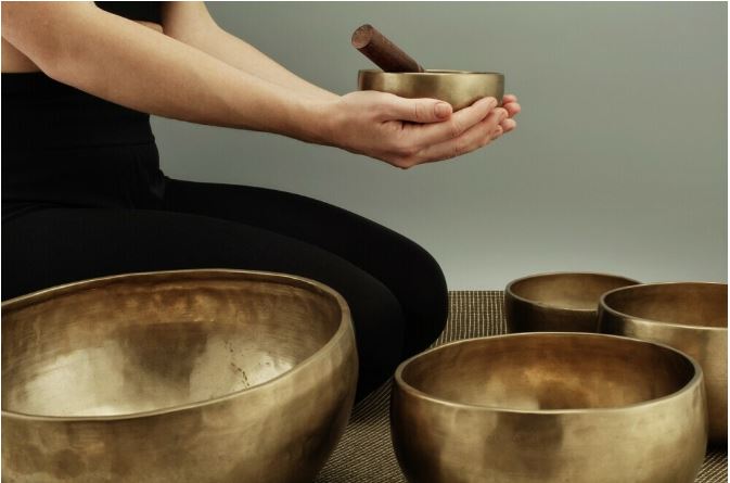 a woman holding a tibetan singing bowl using sound healing as a holistic approach